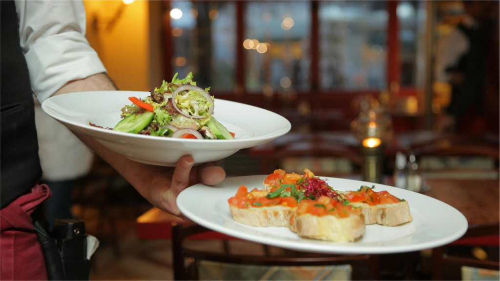 waiter delivering plates of salad and bruschetta