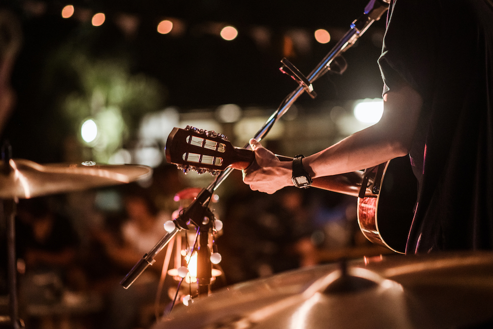 The musicians were playing rock music on stage, there was an audience full of people watching the concert. Concert,mini concert and music festivals.