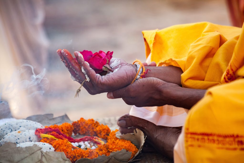Woman holding flowers in her hand at a Hindu worship service.