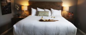 A bed with soft sheets. A wine and cheese board sits atop the middle of the bed in our Meadowlark Room at the Purple Orchid Resort & Spa.