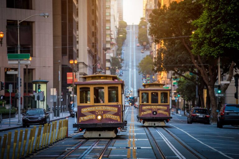 Classic view of historic traditional Cable Cars riding on famous California Street in beautiful early morning light at sunrise in summer, San Francisco, California, USA.