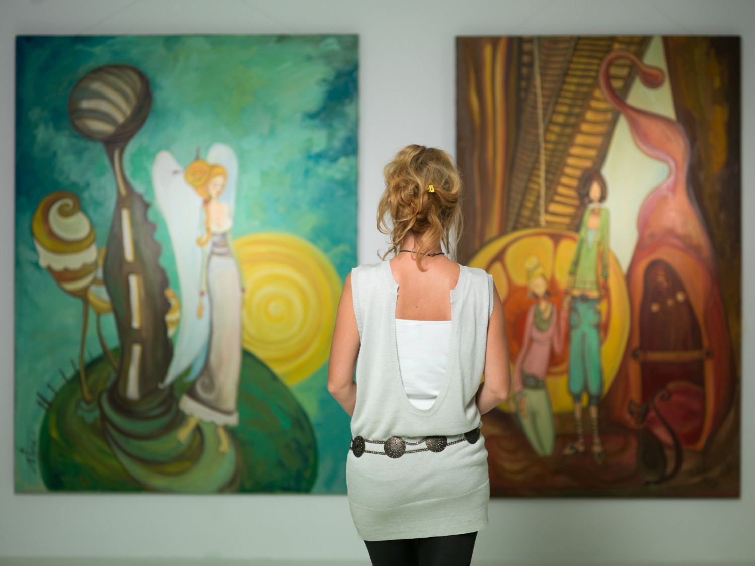 A woman standing in an a studio viewing two pieces of artwork on the wall at SF Open Studios.