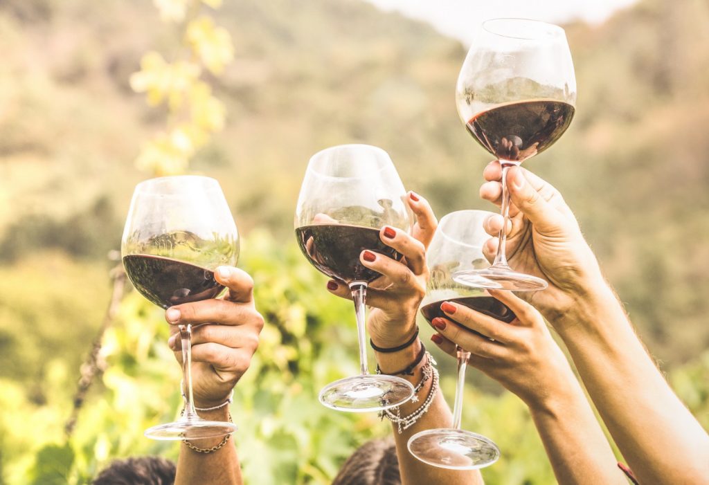 Four women raising a toast with red wine.