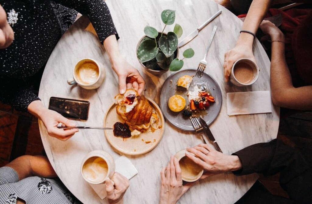 four friends are out to brunch eating pastries and drinking coffee
