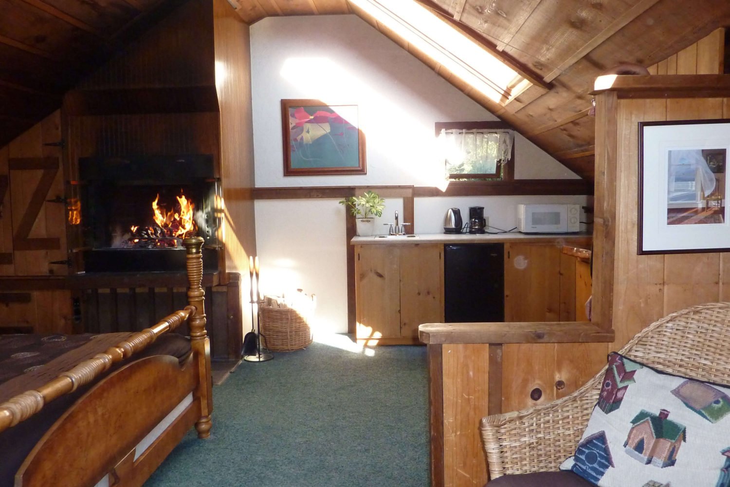 Tree House fireplace next to kitchen and bed with wicker chair in foreground