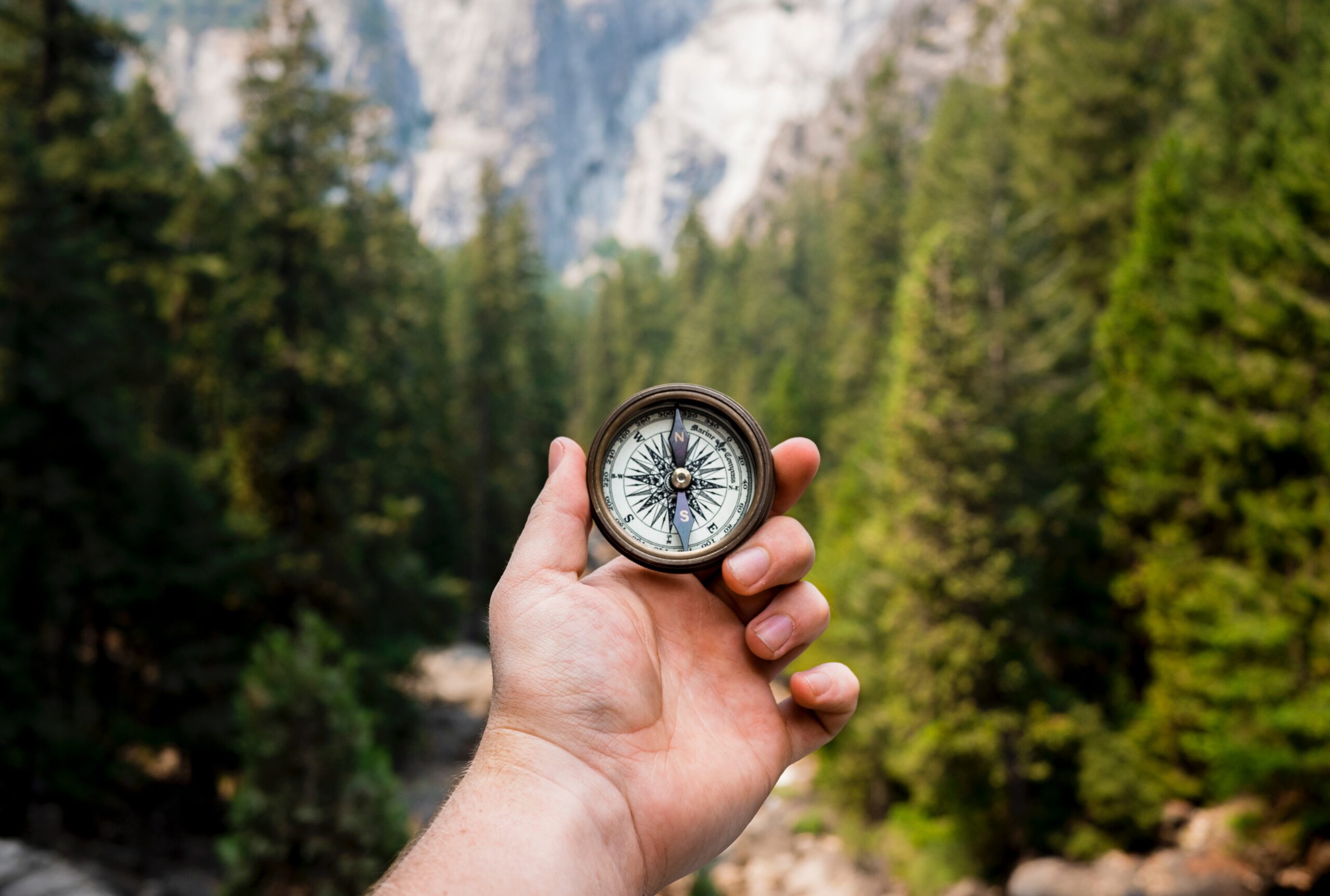 Person holding a compass out in a mountain environment