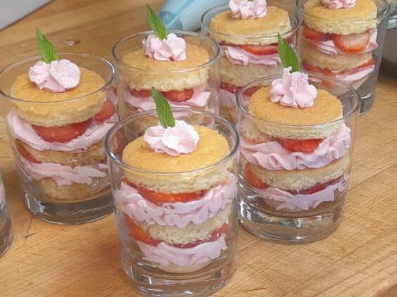6 shot glasses filled with strawberry shortcake layered with strawberry icing