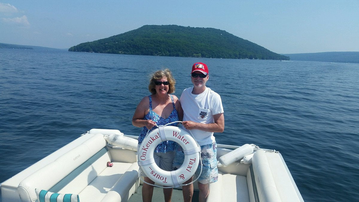 A couple holding a life preserver in the foreground with the words OnKeuka Water Taxi & Tours