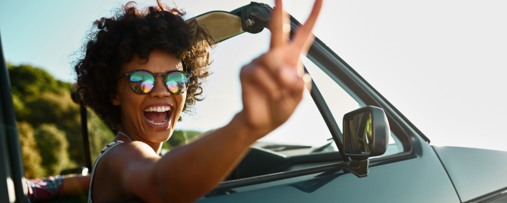 woman giving peace sign in convertible