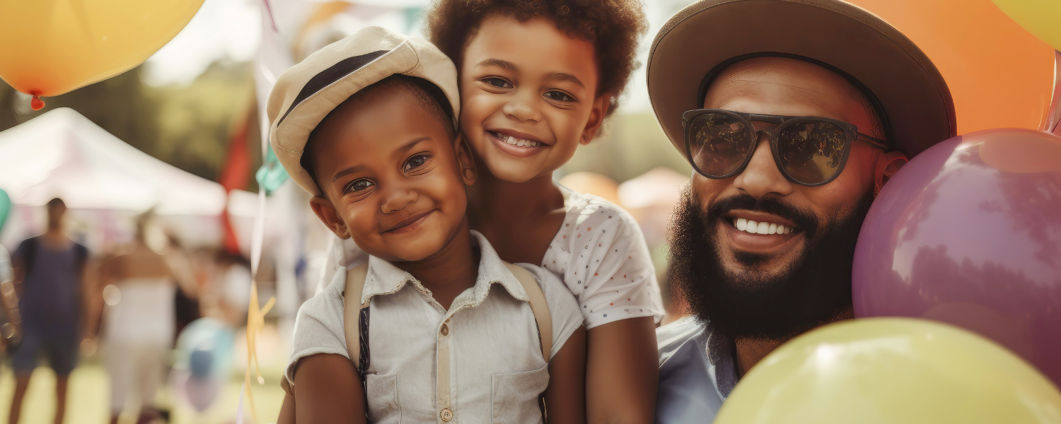 man and two children at outdoor event surrounded by balloons
