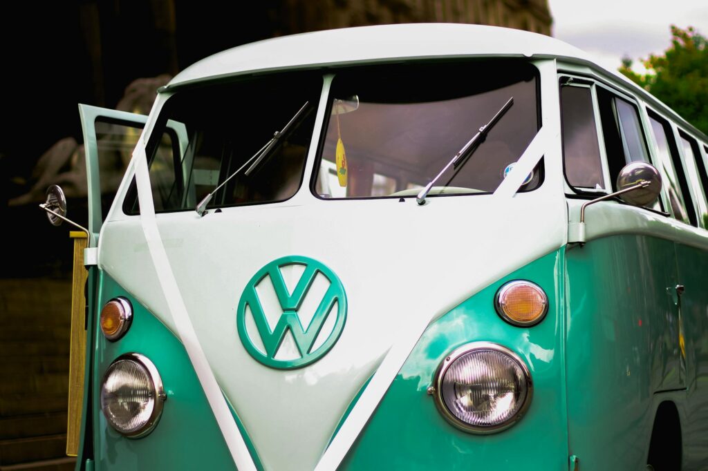 Front view of a teal and white Volkswagen bus. VW logo prominently displayed.