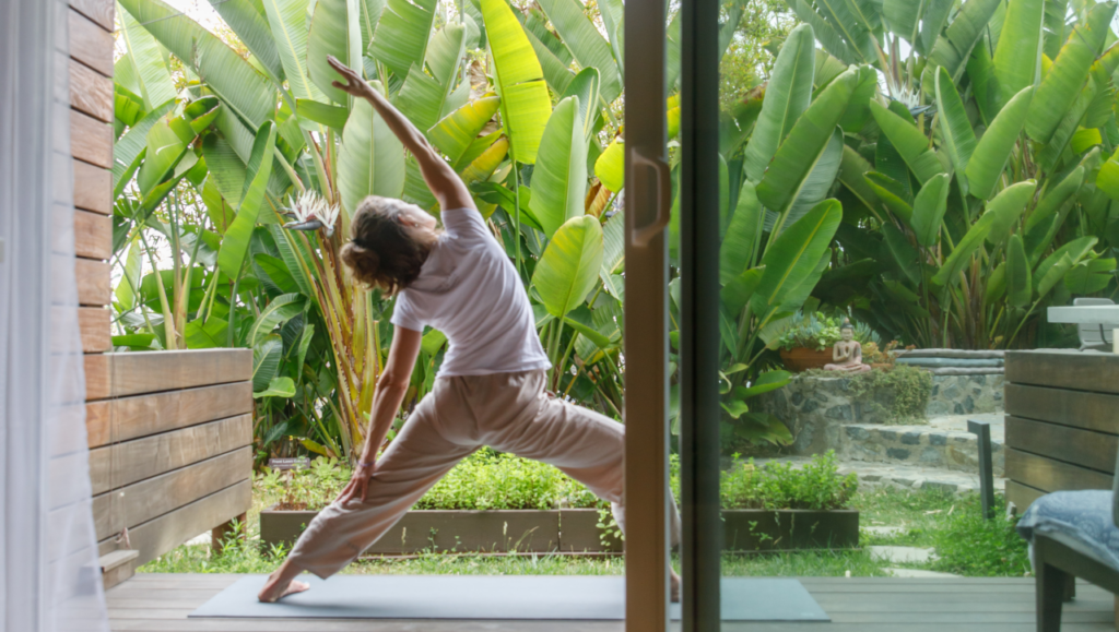Woman practicing yoga in a serene open-air space surrounded by lush tropical greenery at Inn at Moonlight Beach in Encinitas.
