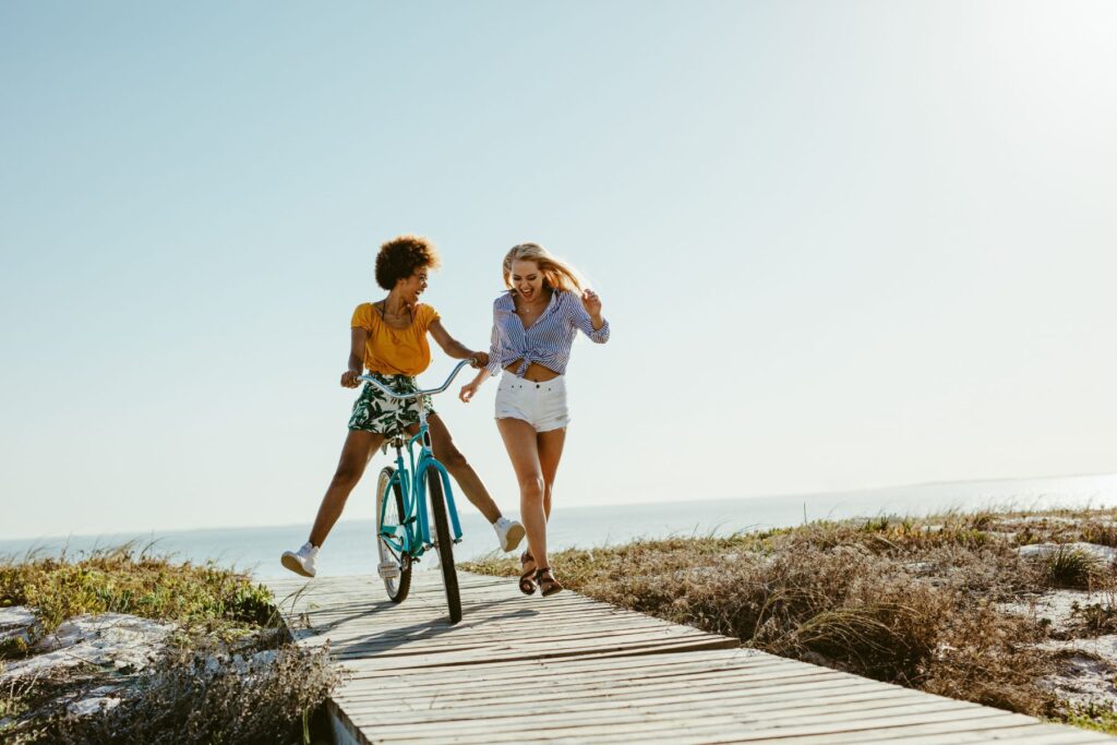 two friends enjoying biking and running down the boardwalk on amelia island
