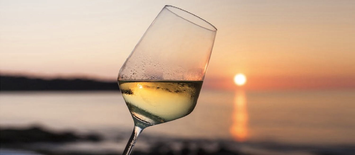 Wine glass with sunset on the beach behind it on Amelia Island