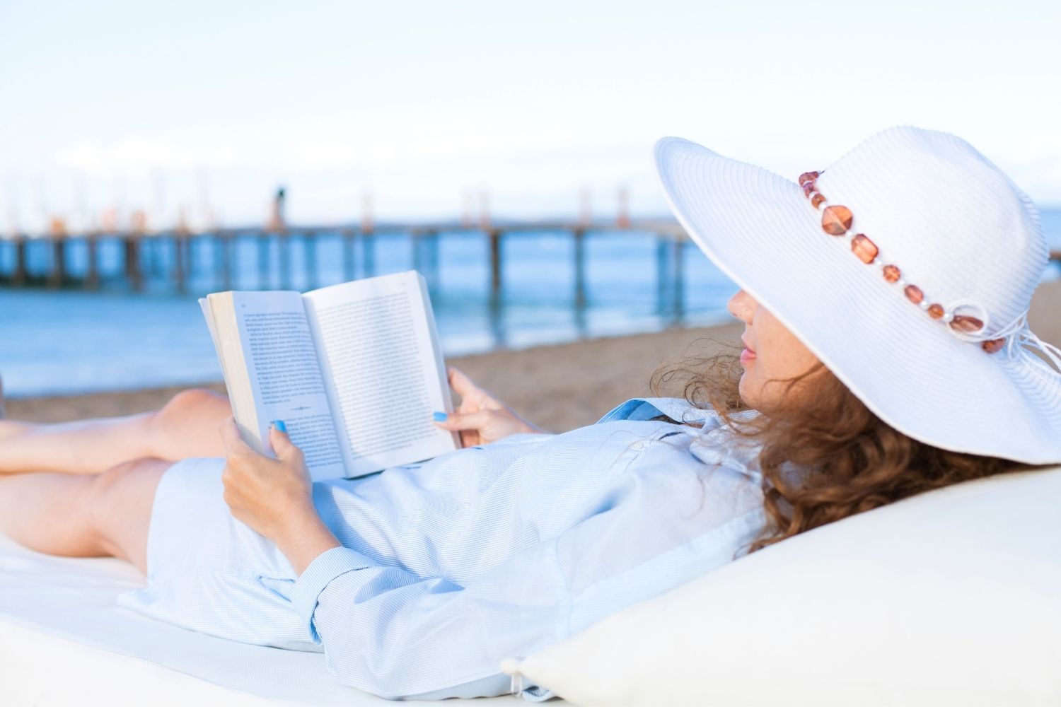 Lady reading a book on the beach.
