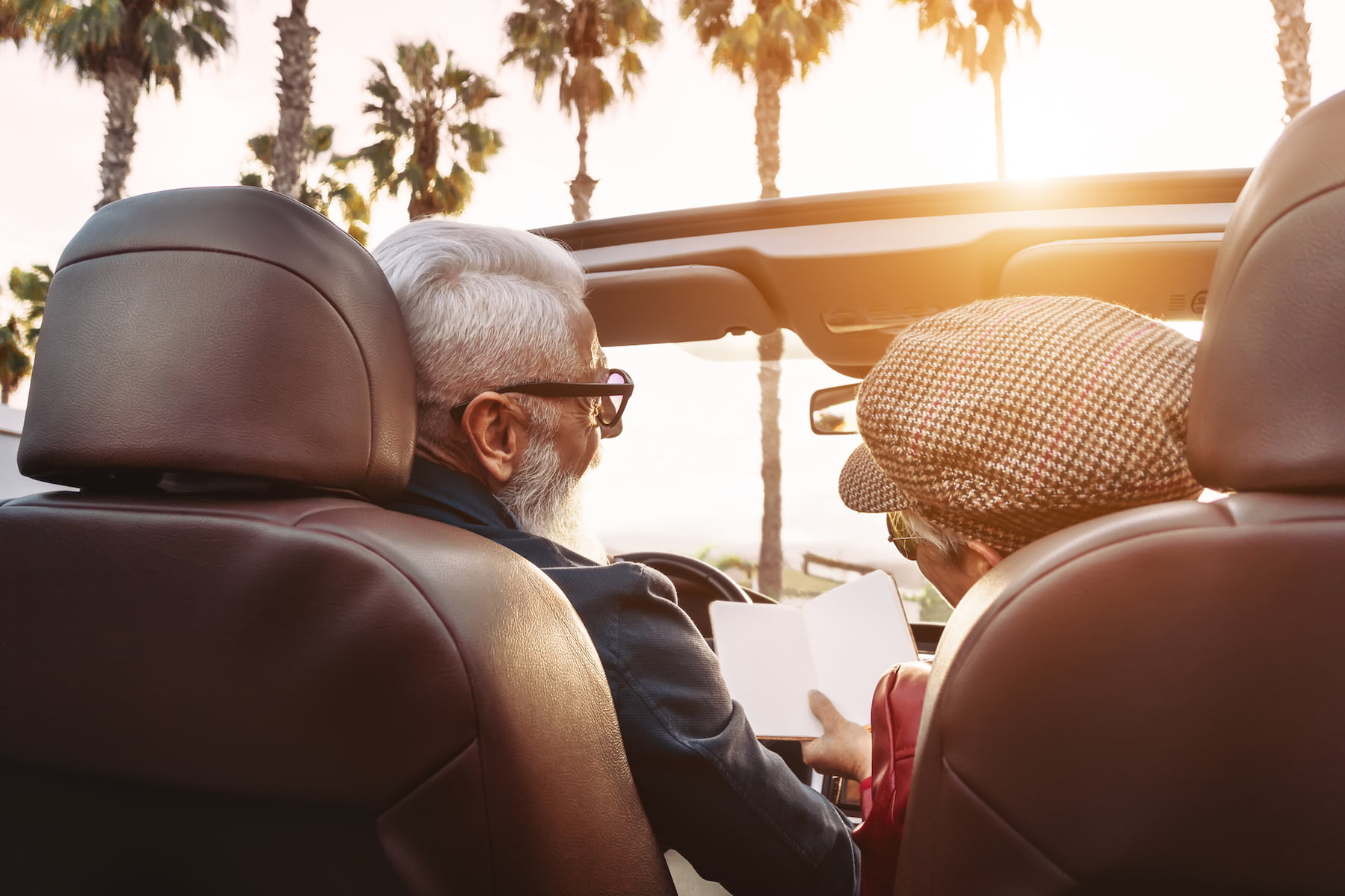 Happy senior couple having fun on new convertible car - Mature people enjoying time together during road trip vacation - Elderly lifestyle and travel transportation concept (Happy senior couple having fun on new convertible car - Mature people enjoyin