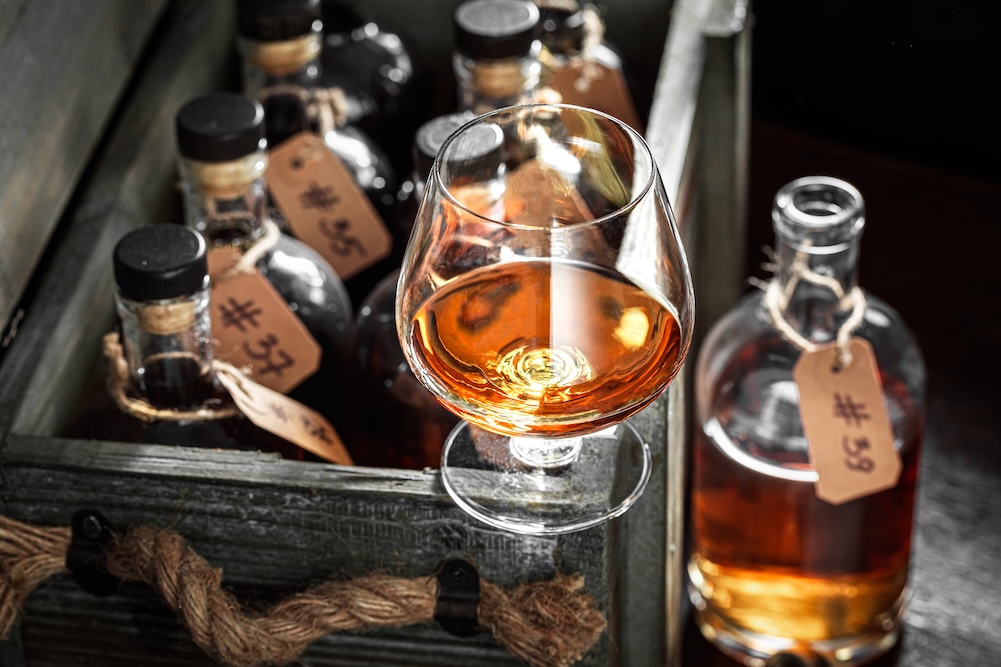 Old and good cognac in old distillery warehouse. Bourbon with ice in a glass in the distillery.