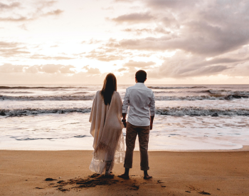 couple standing on beach holding hands
