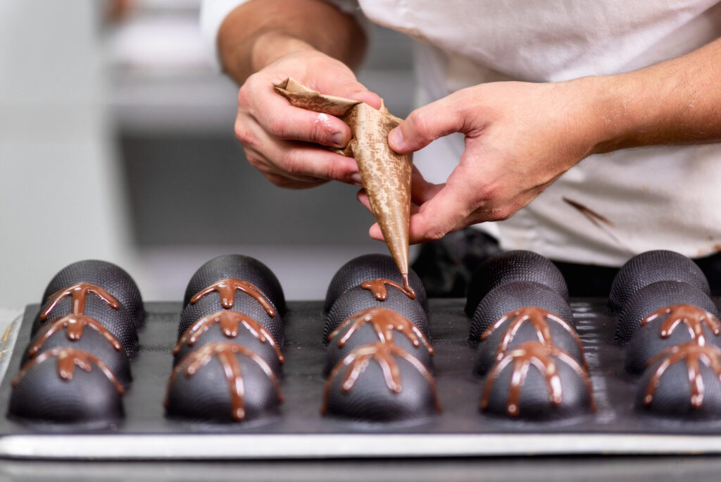 Chocolate maker decorating truffles. - Professional confectioner making chocolate sweets at confectionery shop.