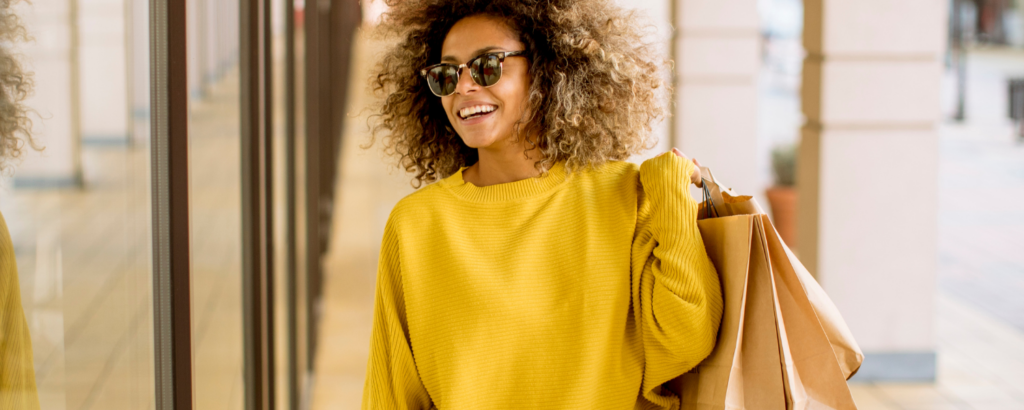 young woman in yellow sweater with shopping bags