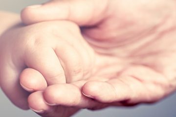 Close up of person holding baby hand