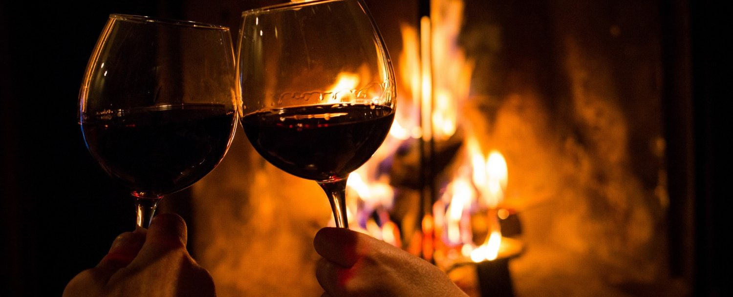 Couple toasting wine glasses in front of fireplace