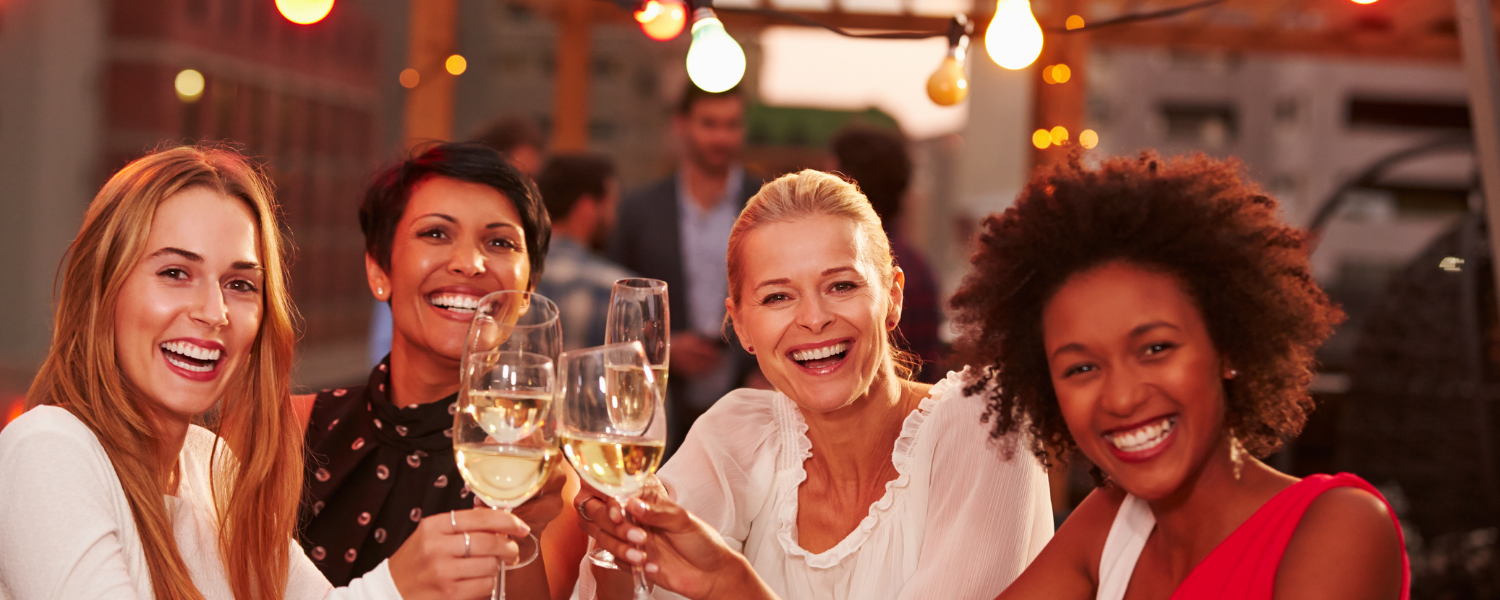 Four women smiling and toasting wine glasses