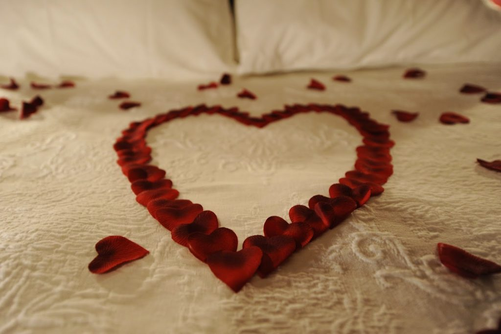 Rose petals in the shape of a heart on a bed