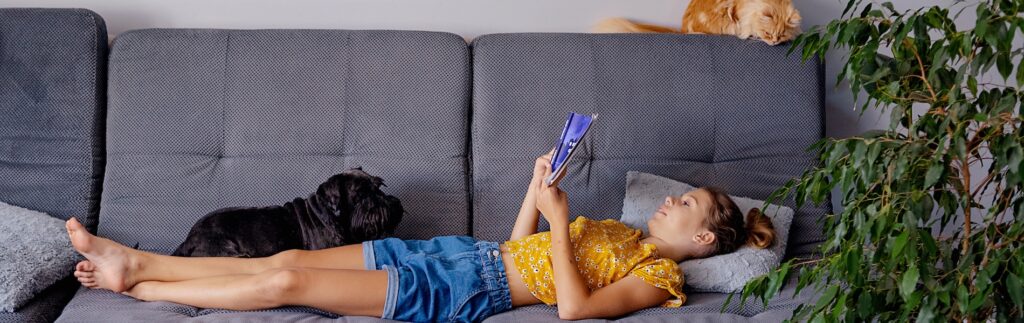 girl reading on a couch, taking a break from looking at a screen