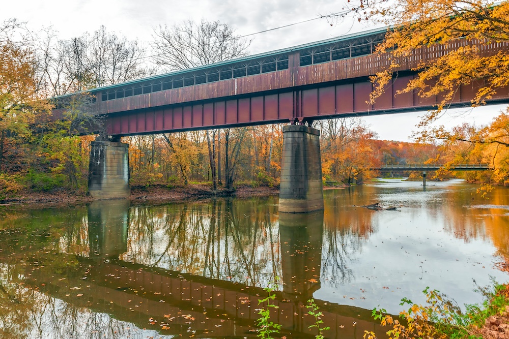 The Bridge of Dreams is a covered Bridge spanning over Mohican river in a fall season. The Bridge of Dreams is a part of Mohican Valley Trail. Knox County. Ohio. USA