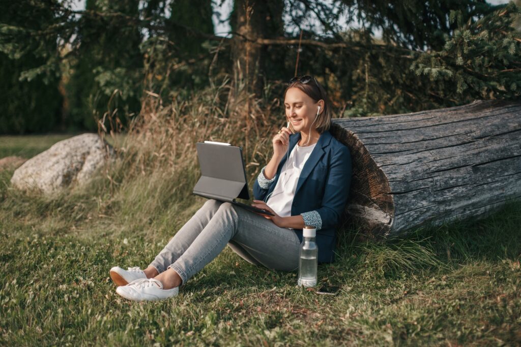 Workation outdoor. Woman working on laptop in park. Distant remote job work during quarantine coronavirus covid-19. Student studying learning online. Video blogger doing live stream.