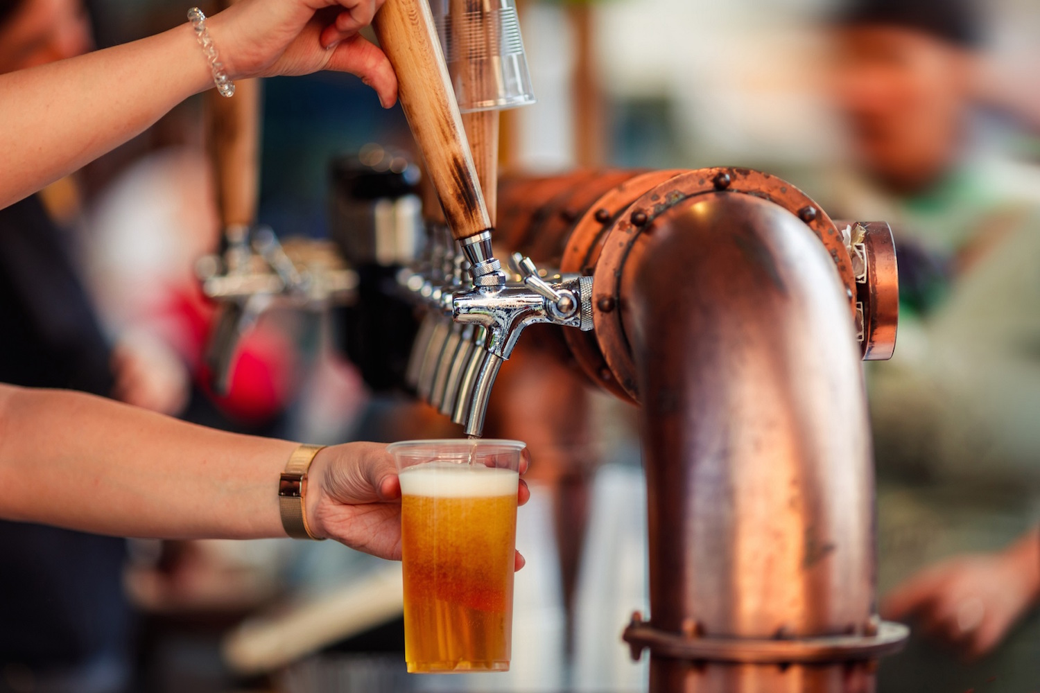 Beer tapping with traditional taps into a plastic cup and colorful blurred background