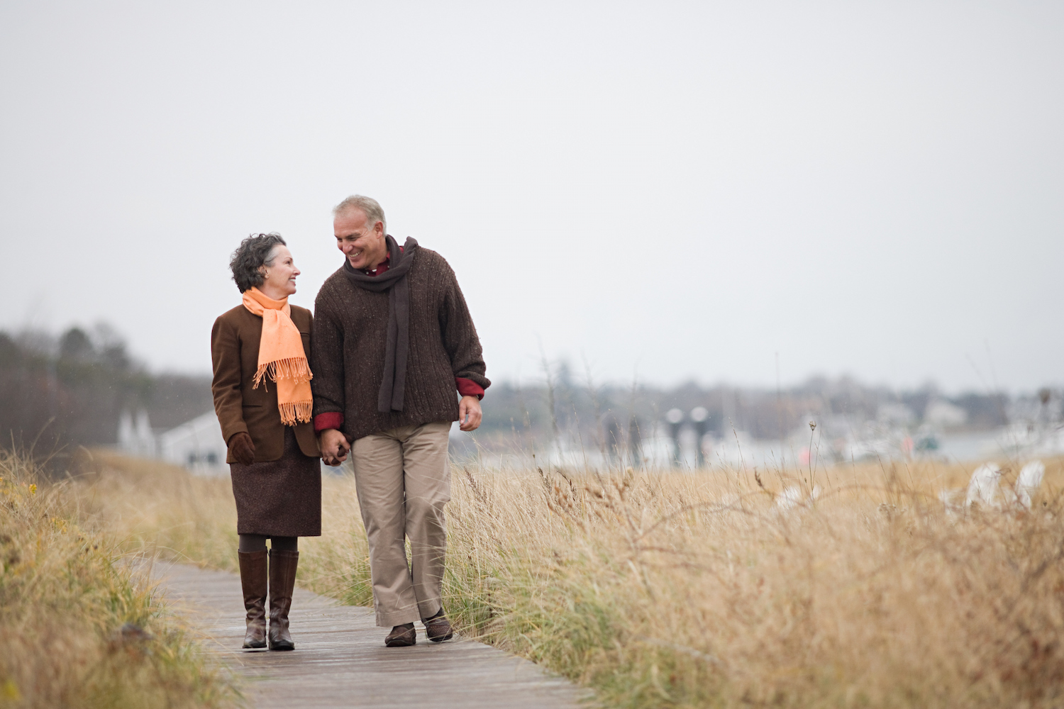 Couple walking next to a body of water in the fall.