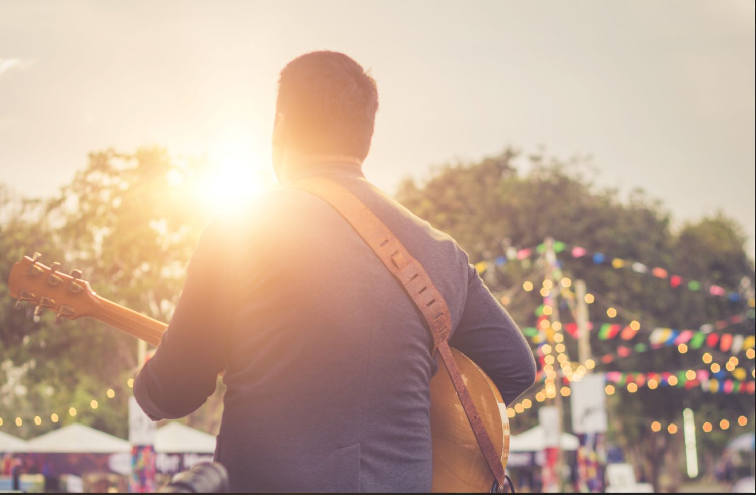 Guy playing guitar at an outdoor concert.