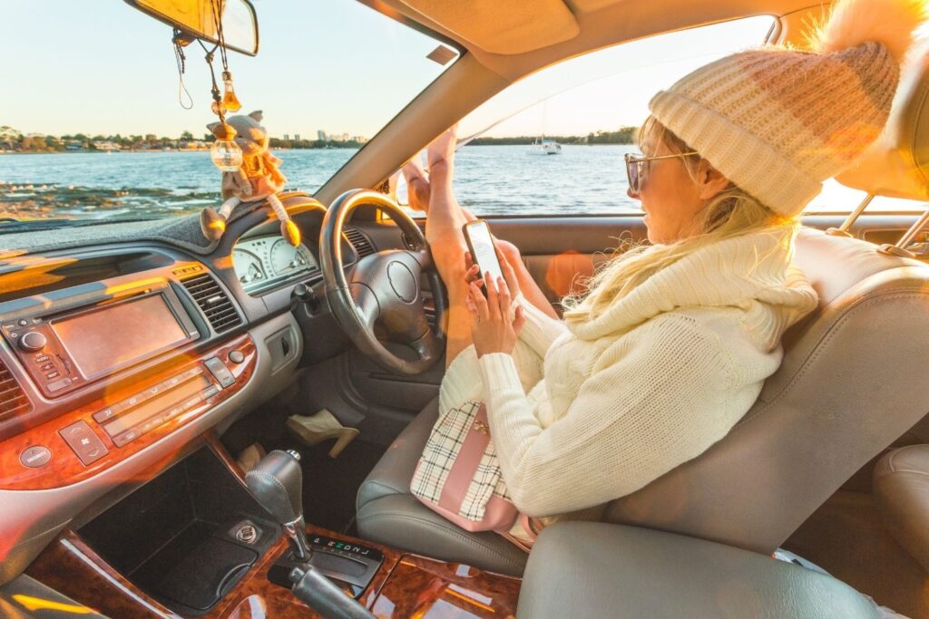 Woman sitting in a parked car en route to a destination on a road trip.