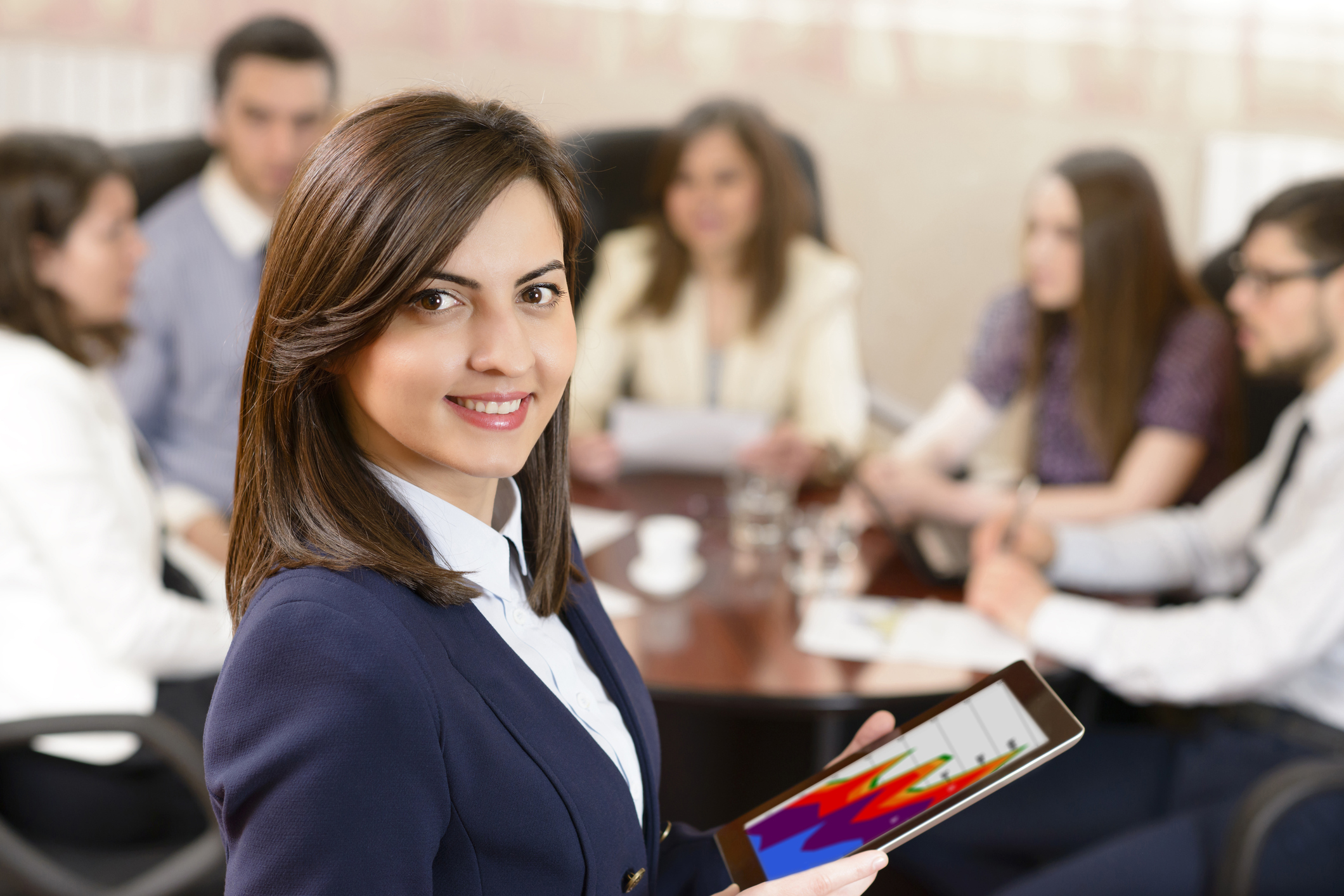 a smiling business woman holding a tablet at a business meeting