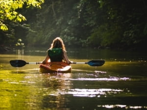 Women kayaks down a calm river