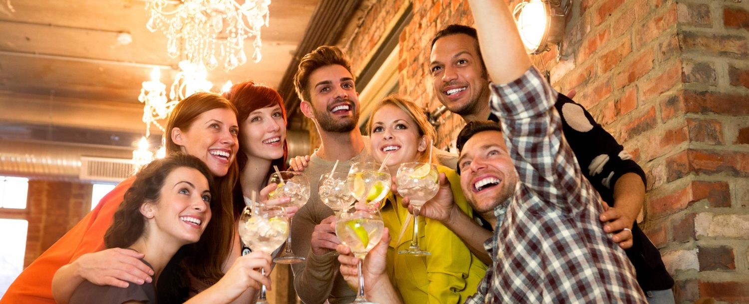 A group of young adults posing for a selfie during happy hour