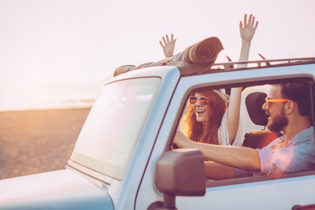 Couple riding along the beach in a jeep