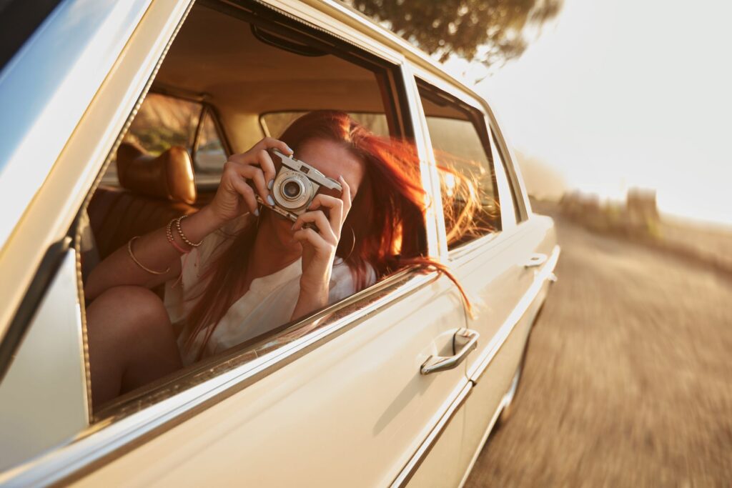 Experience day trips from Amelia Island like this girl taking in the local surrounding withs a camera in a car.