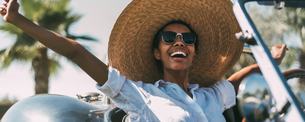 woman in convertible wearing a sun hat