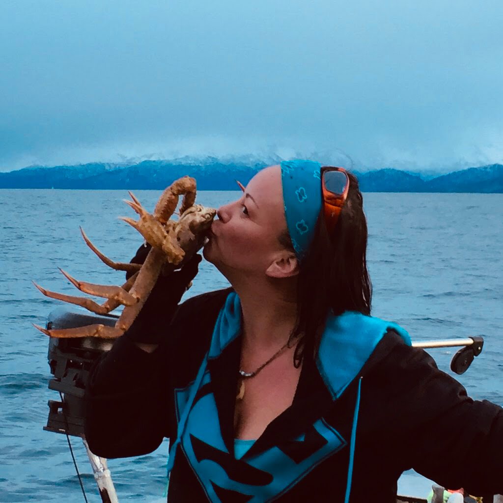 Woman kissing Tanner crab with ocean in the background