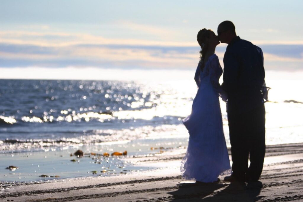 Couple kissing in wedding attire on Bishop's Beach.