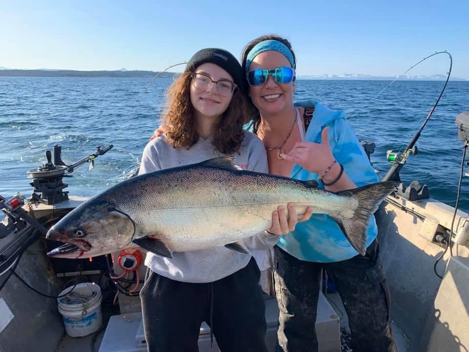 Woman and daughter holding a salmon on a fishing charter.