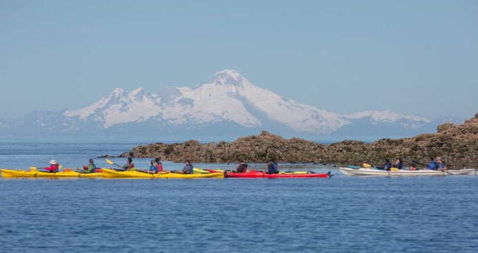 Kayakers kayaking during the day with a mountain peak in the background