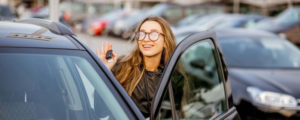 White woman with glasses getting into a rent-a-car