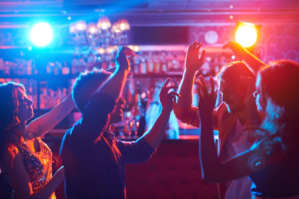 A couple of happy friends dancing at a bar.