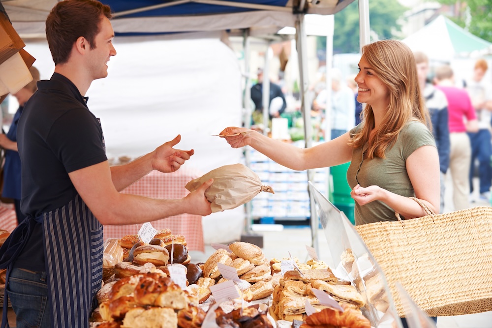 Famers market visitor purchasing bread from a vendor