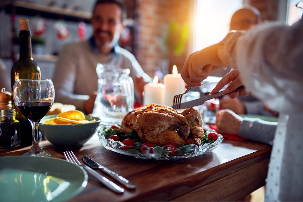 Closeup of someone cutting into a turkey sitting on a dining table