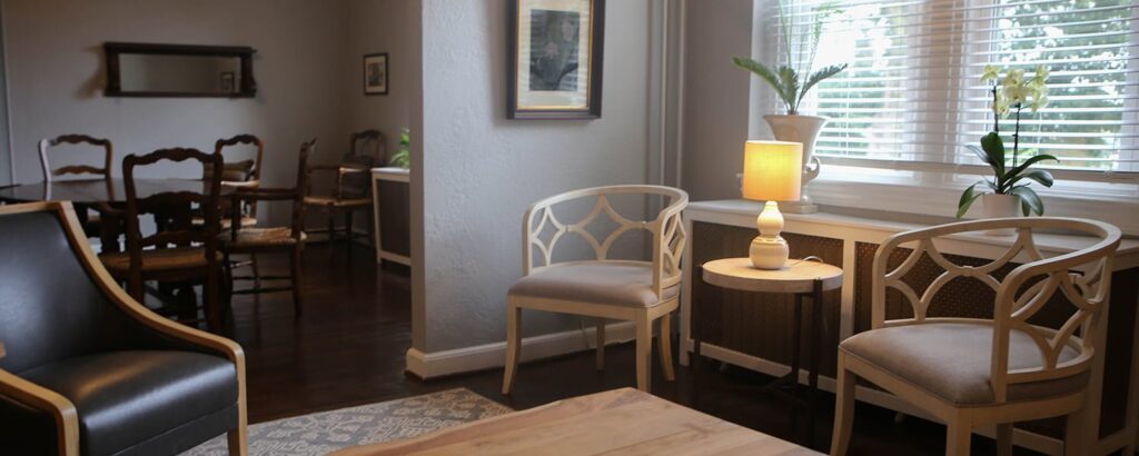 A white wooden chair with curved diamond shapes in its frames sit in the corner of the William Sayre Suite.